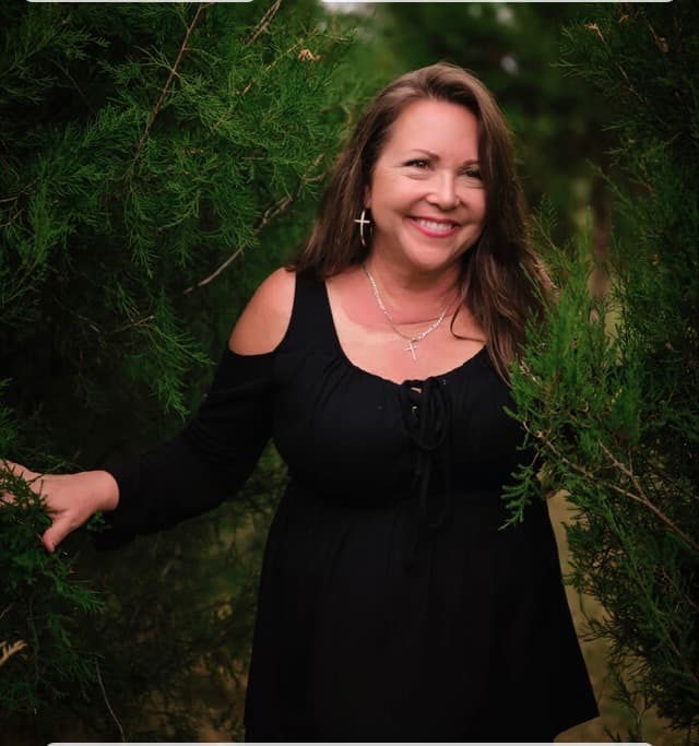 Smiling among the cedar trees at Aimee's Acres